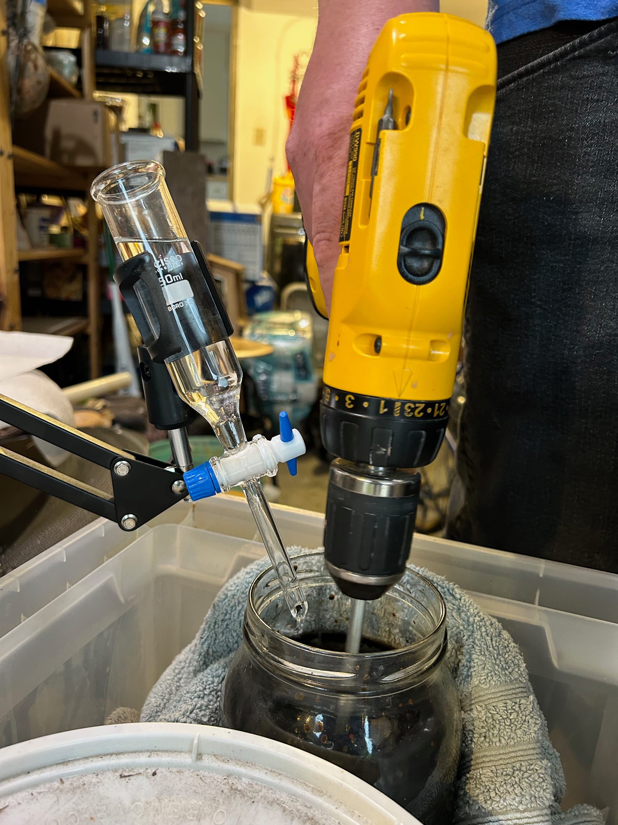 a titration device and a drill both stuck into a glass jar