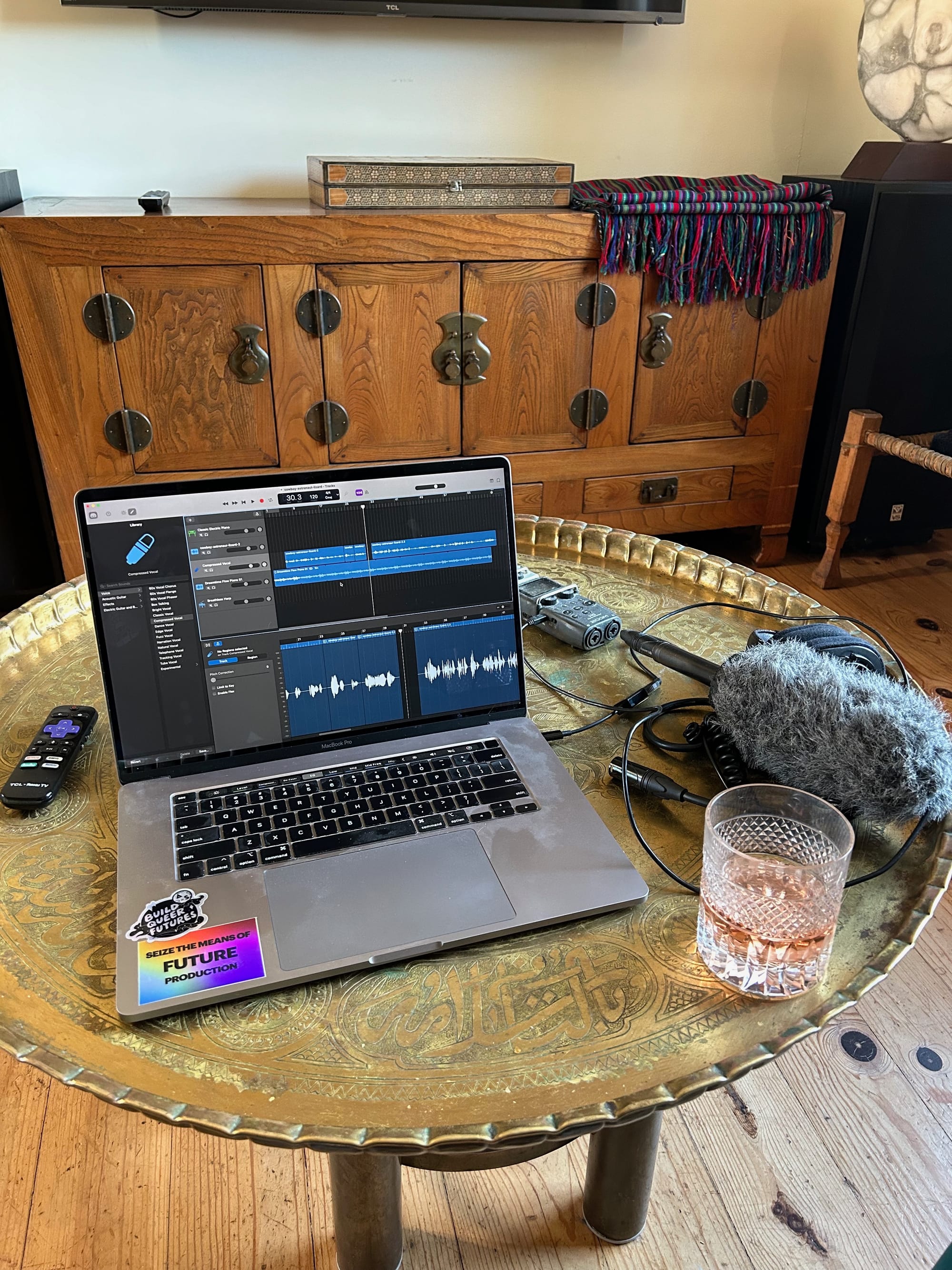 a bronze table with a computer and microphone on it, the computer has Garageband up