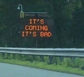 a highway sign that says "it's coming it's bad"