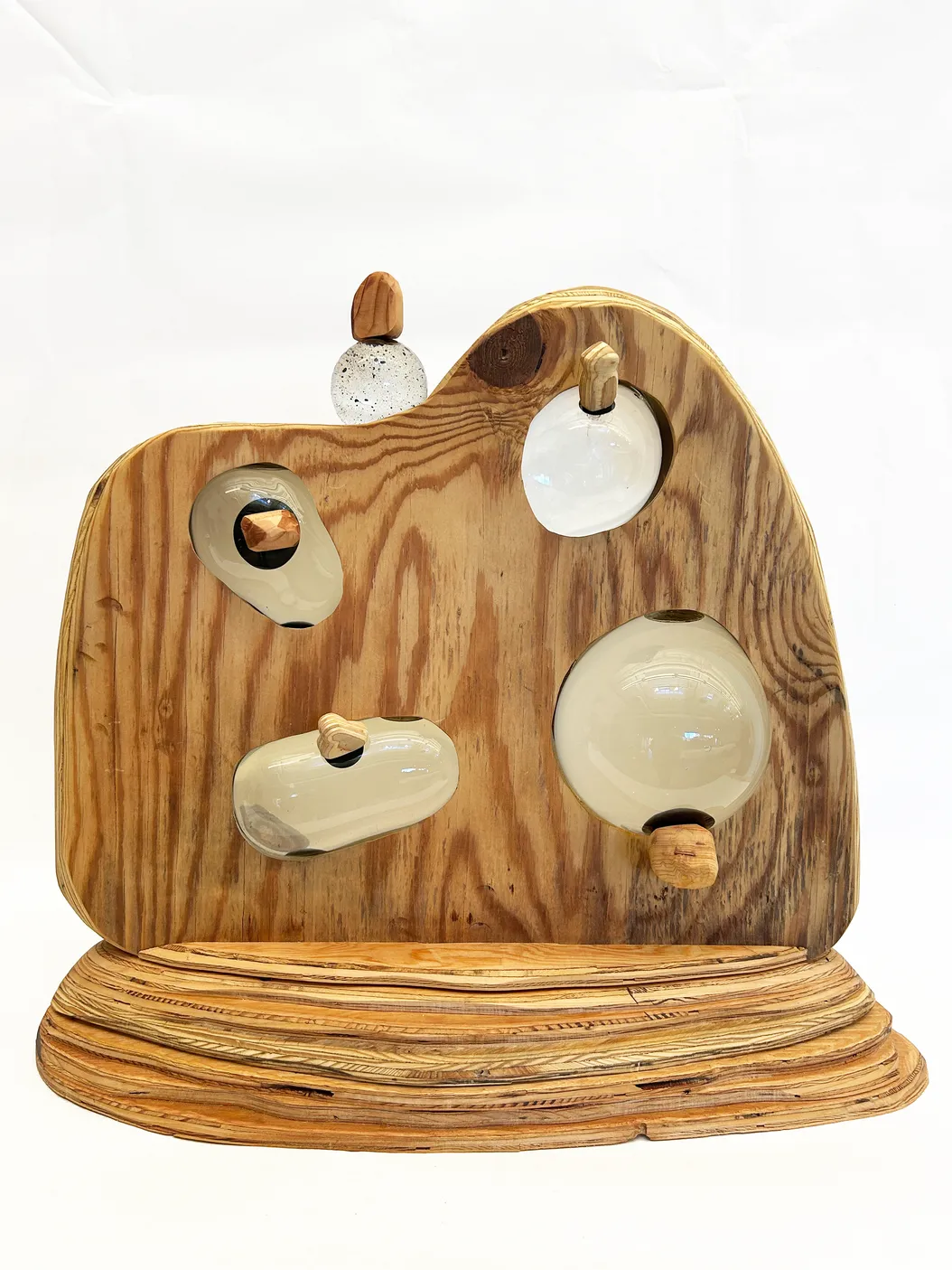 a sculpture made of wood, with five glass orbs embedded in the wood, each filled with water and ferrofluid