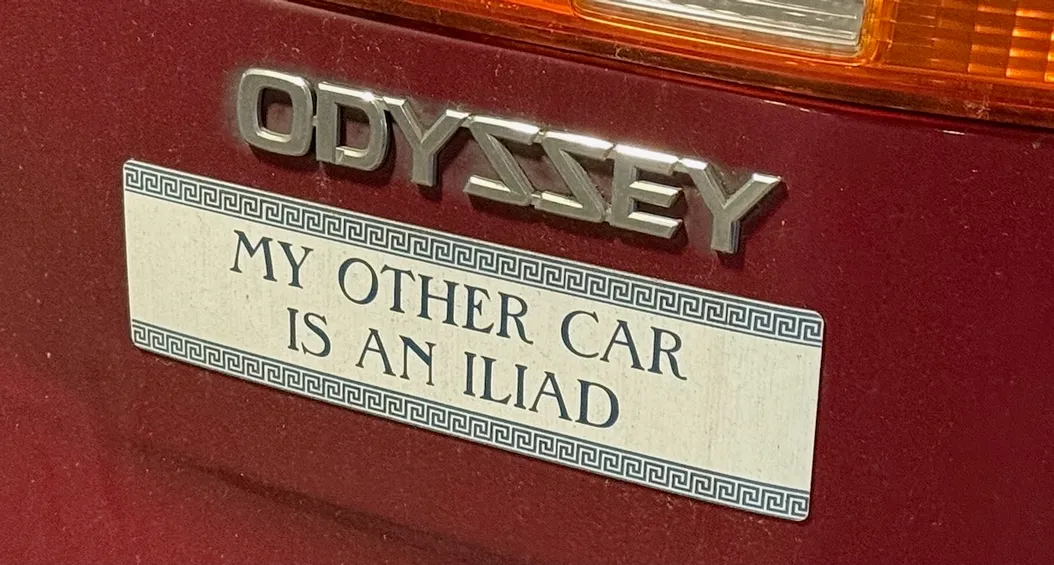 a photograph of a Honda Odyssey logo, beneath which is a sticker that says "my other car is an Iliad"