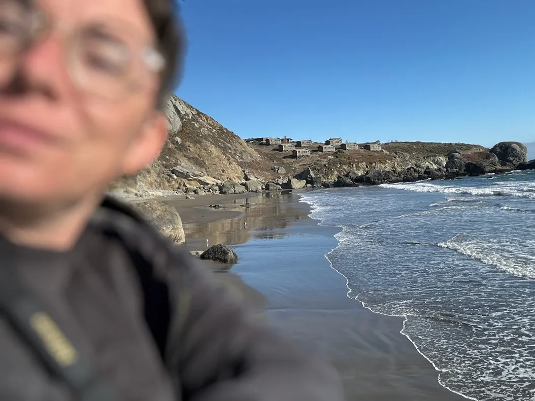 me, very blurry in the foreground - in the background, a row of cabins on a hill along the beach