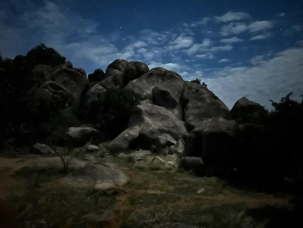A blurry, almost painting like photo of a set of rocks and a muted blue sky with stars in it.